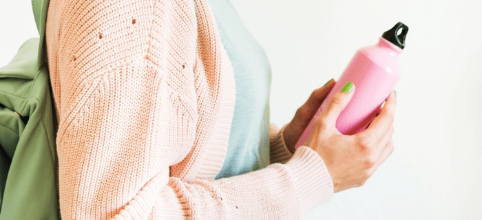 A close up of a woman holding a reusable drink bottle