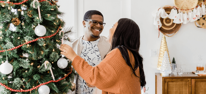 A couple hang decorations on their Christmas tree