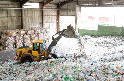 A tractor sifting through piles of plastic