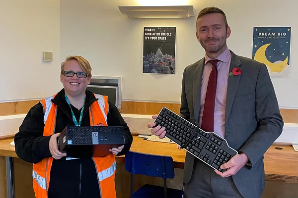 A women and a man standing with a donated keyboard and monitor