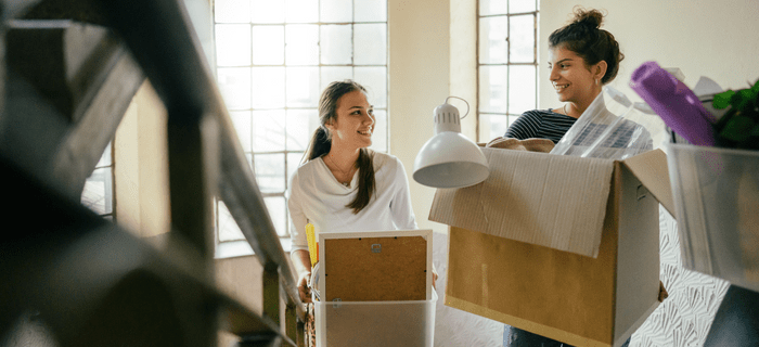 Two female students carry their moving-in boxes upstairs