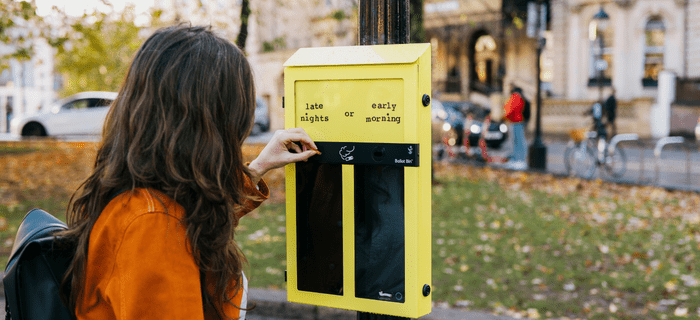 A woman uses a voting bin by putting a cigarette butt into one half of the bin 