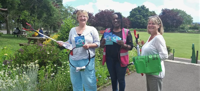 Three people on a litter pick in some gardens