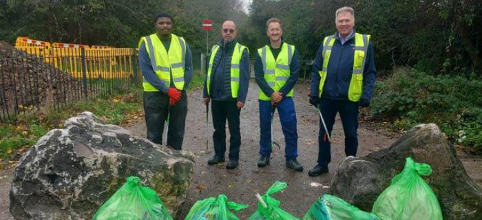 Four people standing in the rain in front of bags of litter that they had just collected