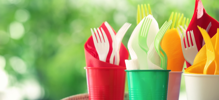 Single use plastic cups filled with plastic cutlery and paper napkins