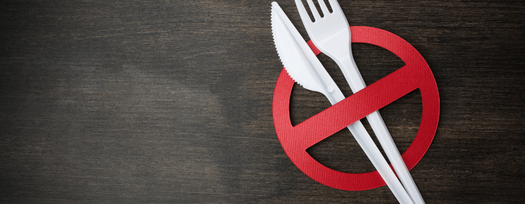 White plastic cutlery behind a red paper 'stop' symbol.