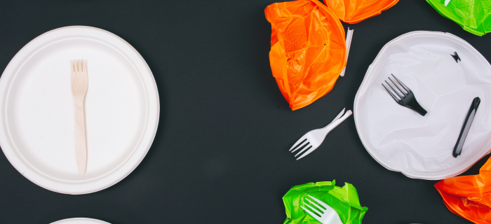 Single-use plastic plates and broken forks on black background.