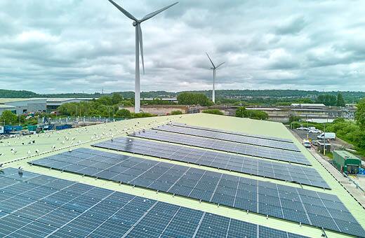 Solar panels on Havonmouth Reuse and Recycling Centre with wind turbines in the background.