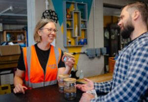 Woman in high-visibility top talking to man at shop counter