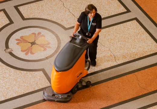 Woman pushing scrubber drier across a floor