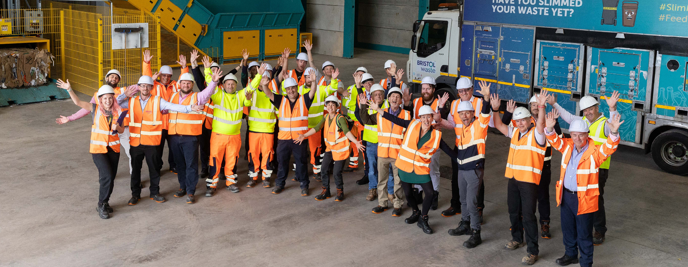 A large group stands in a materials recycling facility