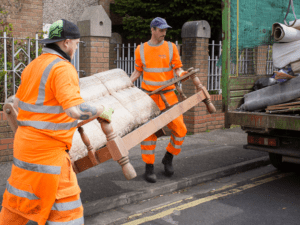 Two Bristol Waste employees in hi-vis carry an old sofa to their truck, ready to take it to be recycled