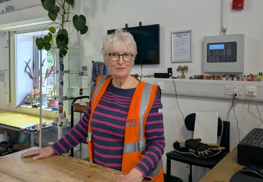 Woman standing at a counter wearing a high-visibility vest on