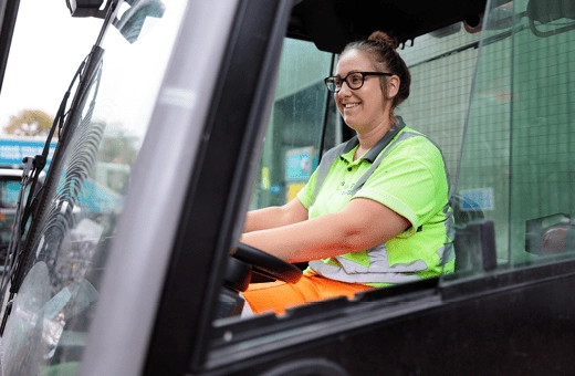 A woman wearing hi-vis driving vehicle in a waste depot