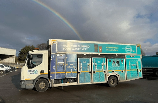 A brightly coloured recycling truck at the end of a rainbow