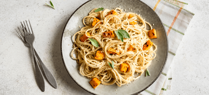 A plate of spaghetti with pumpkin chunks