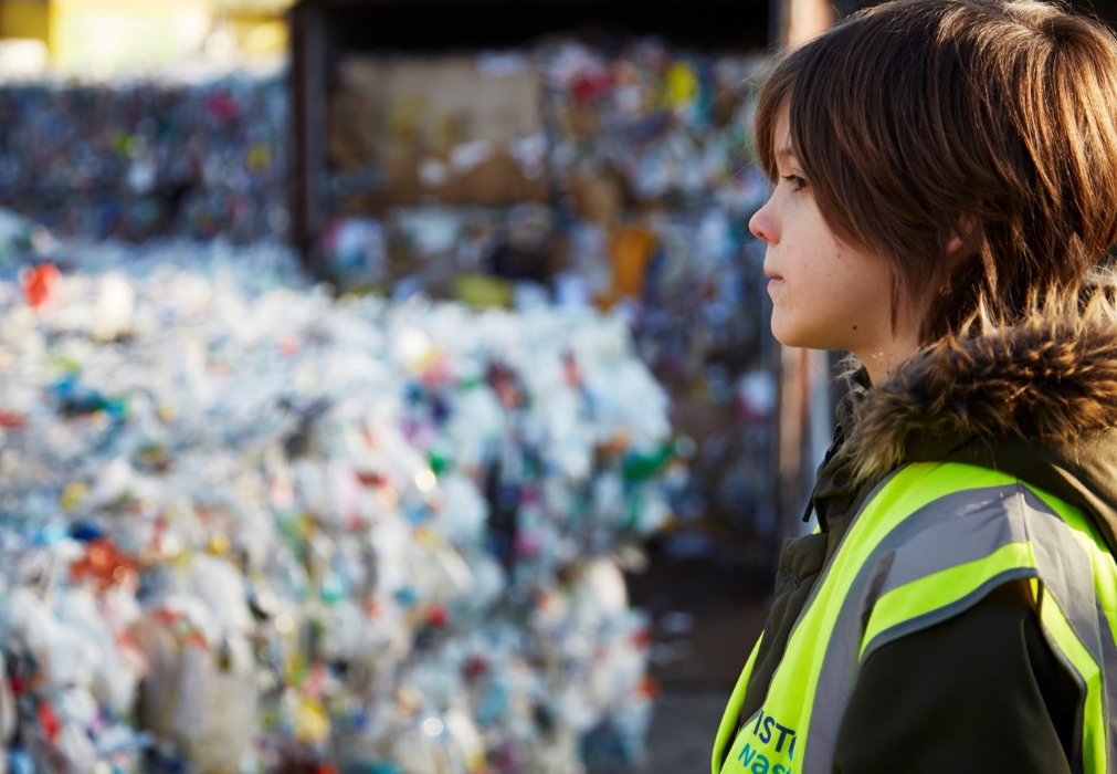 Boy staring at bales of plastic recycling waste