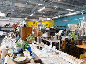 The Hartcliffe Way Reuse Shop, full of pre-loved items to buy. There is glassware in the foreground and lots of furniture and electrical items in the back