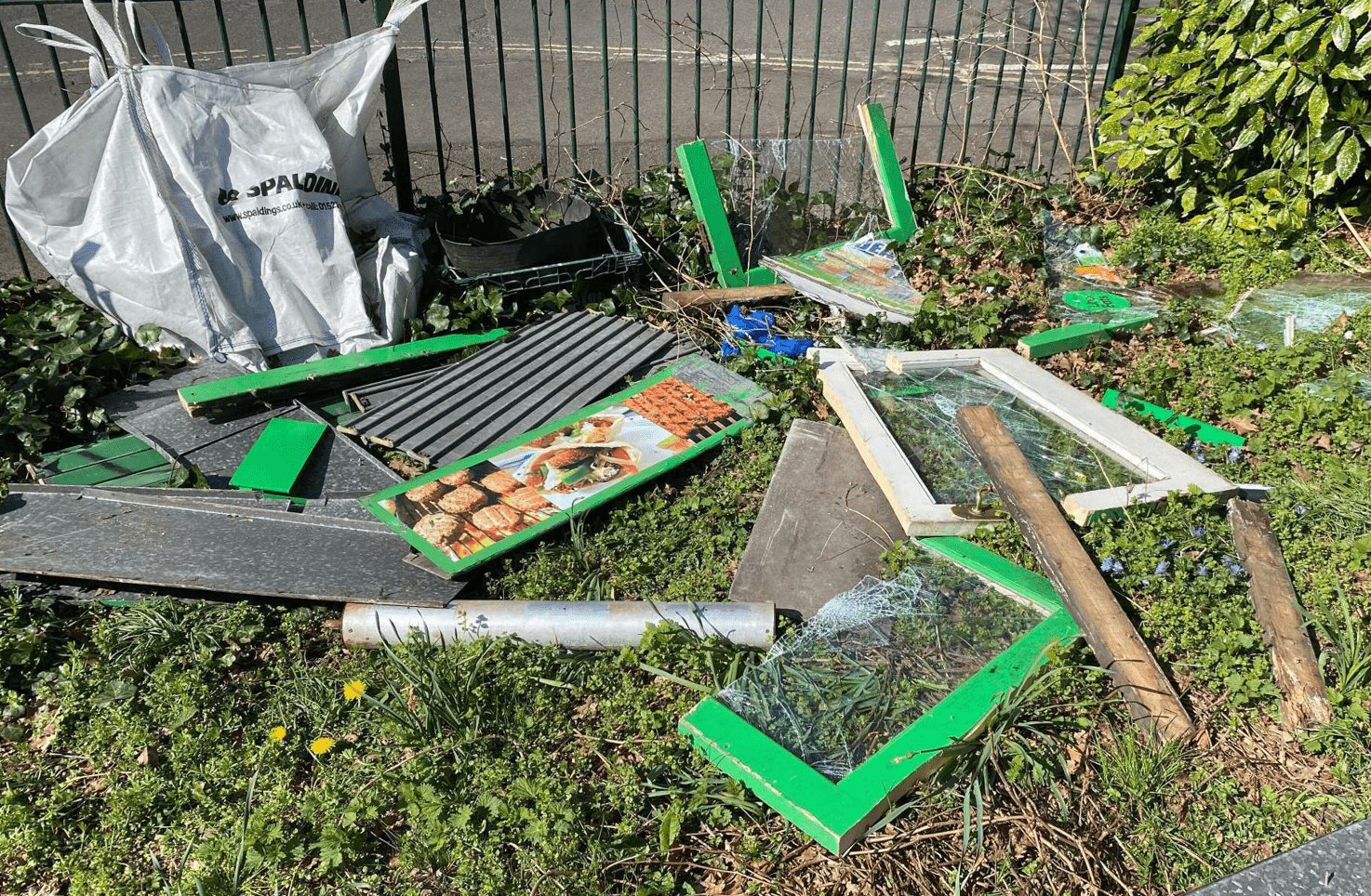A fly-tip on a grassy verge is made up of wood and broken glass