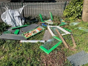 A fly-tip on a grassy area, made up of wood and broken glass