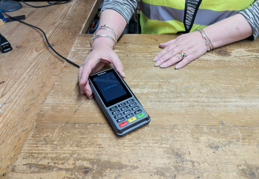 Card payment machine being held by female hands on a counter