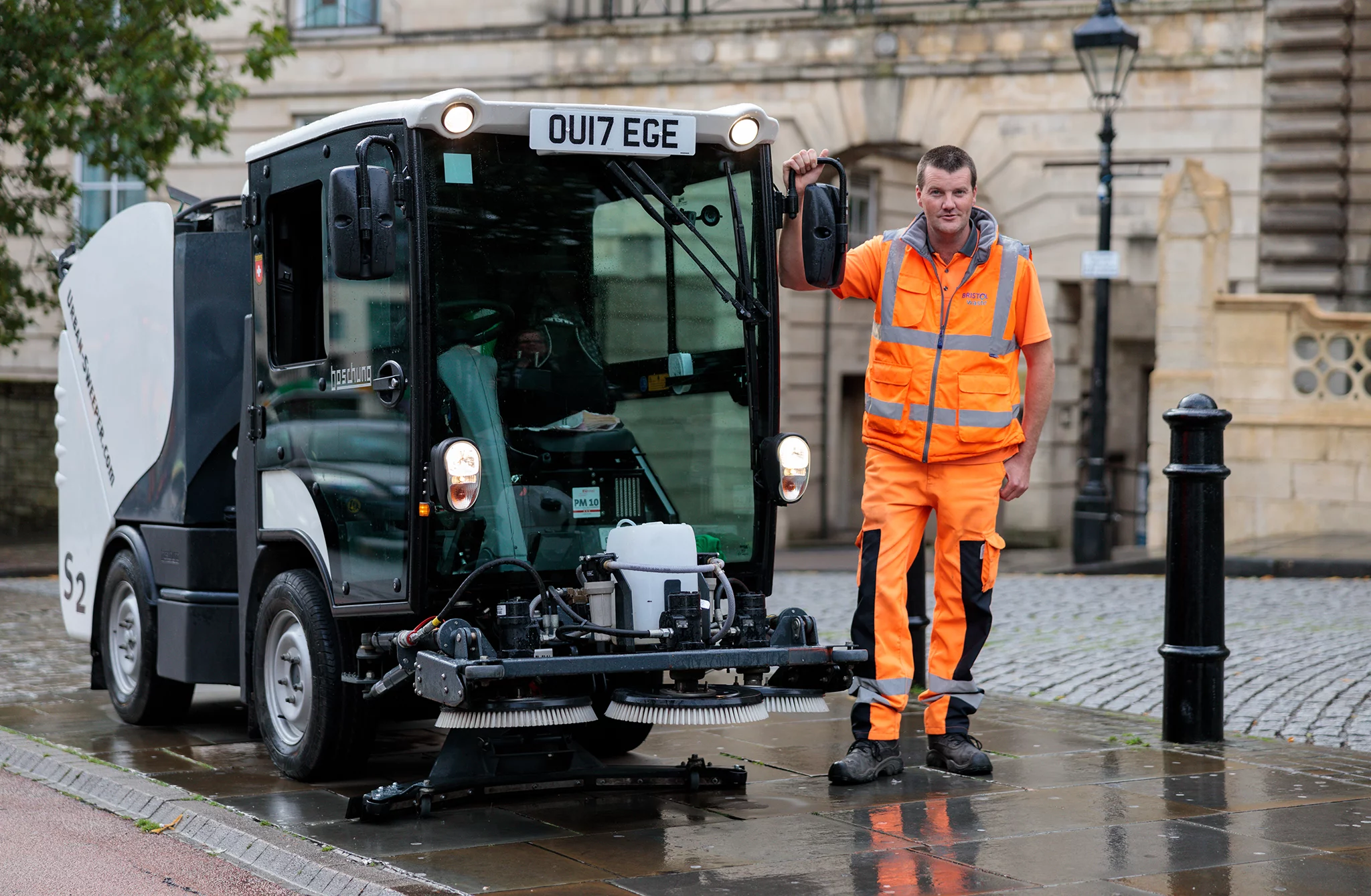 A Bristol Waste street cleansing operative standing next to a street sweeper
