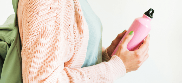 A close up of a woman holding a reusable drink bottle
