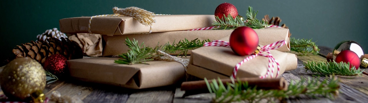 Gifts wrapped in recyclable brown paper with baubles and sprigs of fir tree