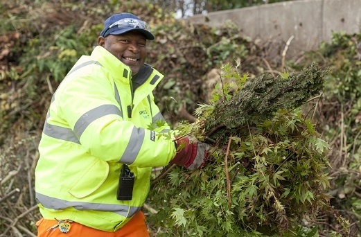 Recycling centre staff member in front of garden waste bay