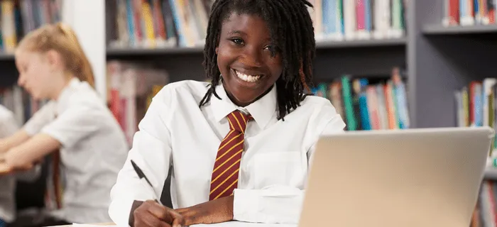 A smiling secondary school student sat at her desk