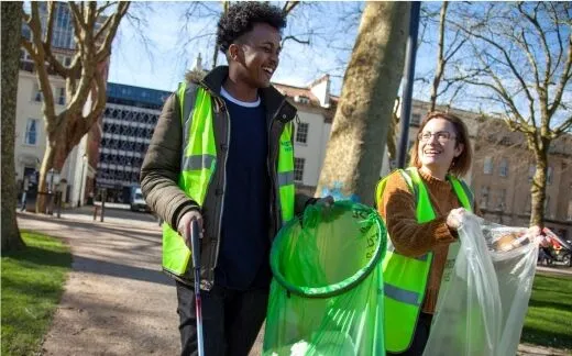 Two students litter picking with litter picks, bags and high-vis
