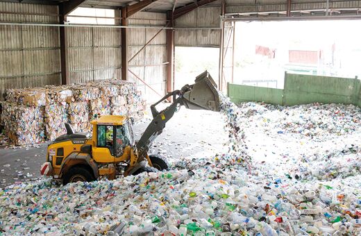 A tractor sifting through piles of plastic