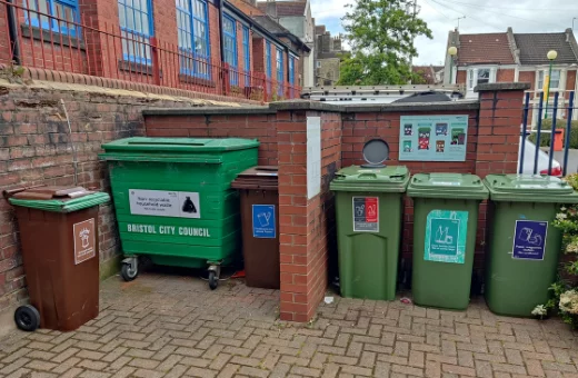 Large Bristol Waste recycling bins in front of a brick wall.
