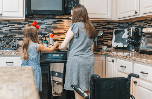 A mother and daughter cooking together, a wheelchair is visible in the kitchen