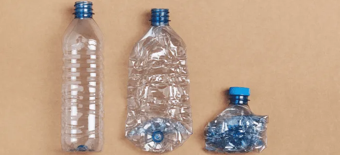 Three plastic bottles on a plain background showing how squashing a bottle can make it smaller. The first bottle isn't squashed, the second bottle is flattened, and the third bottle is compressed down into a fist-sized ball.