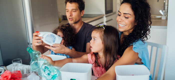 A mum, dad and two daughters sort recycling together at the table.