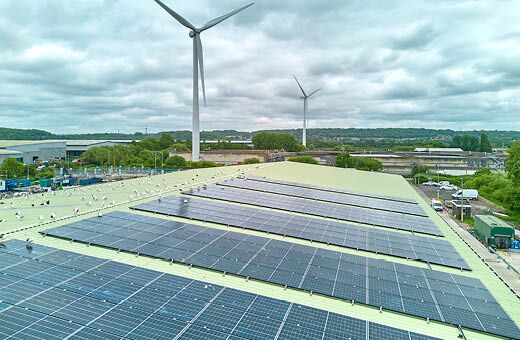 Solar panels on Havonmouth Reuse and Recycling Centre with wind turbines in the background.