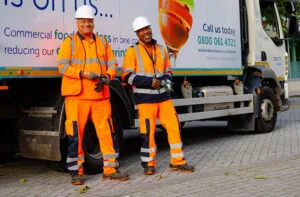 Two men dressed in high visibility clothing in front of a waste collection truck