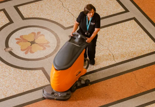 Woman pushing scrubber drier across a floor