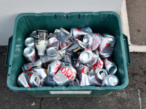 A green recycling box full of squashed cans