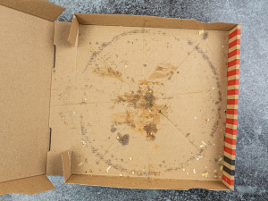 An empty cardboard pizza box, the box is quite greasy