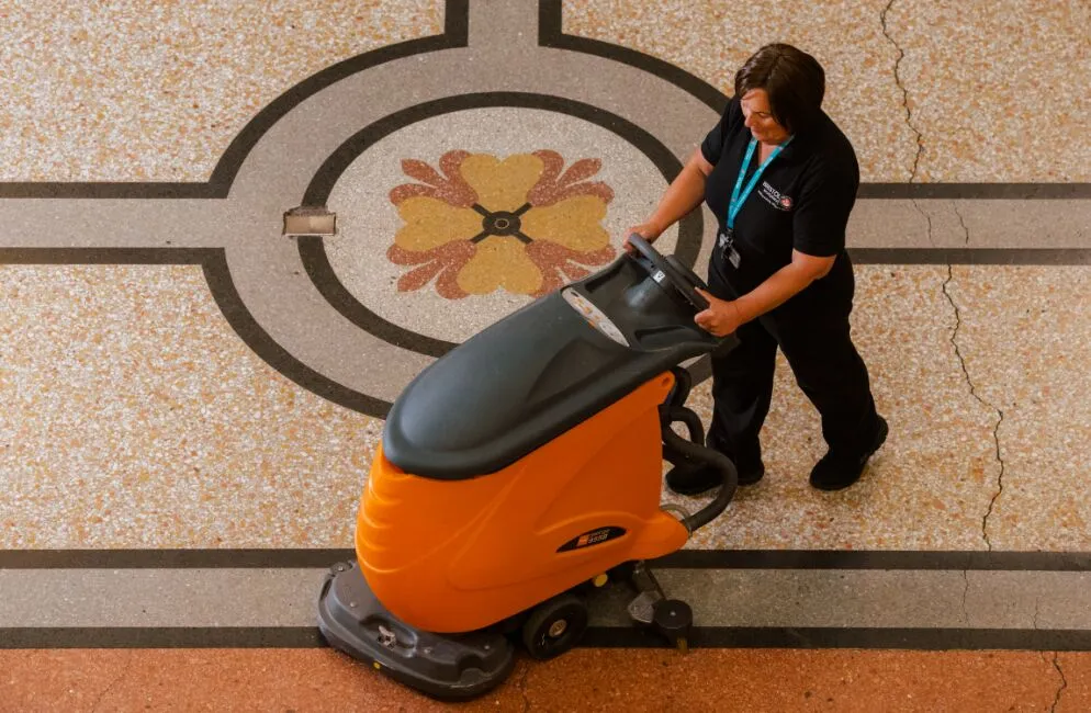 Woman pushing a scrubber machine across the floor