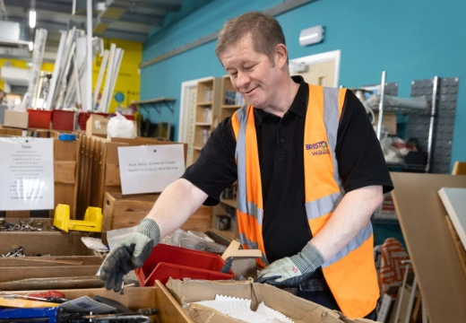 Reuse volunteer in hi-visibility vest and t-shirt putting items out on a shopfloor