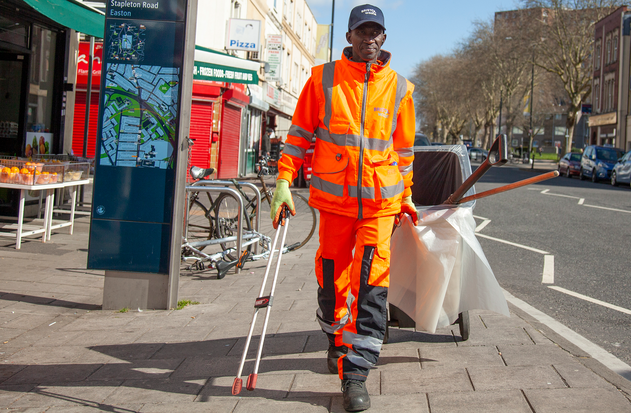A Bristol Waste street cleansing operative litter picking a sunny street in Bristol