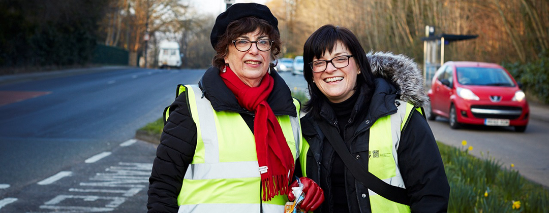 Two smiling woman standing next to a road in Bristol
