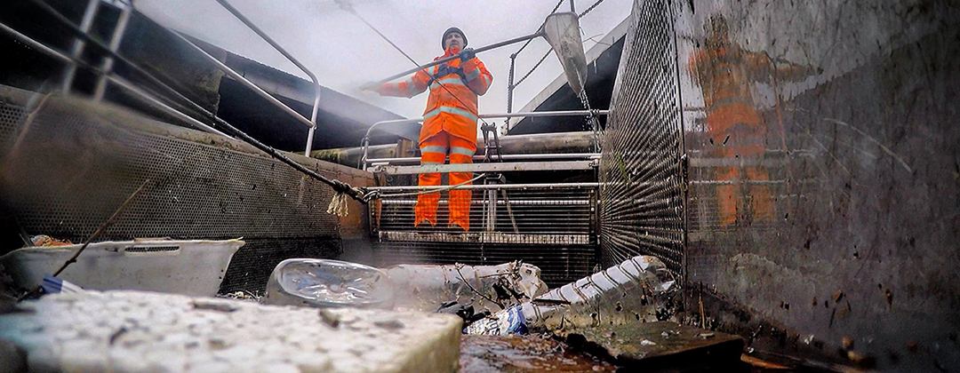 A man in hi-viz with a net to scoop litter out of Bristol harbour