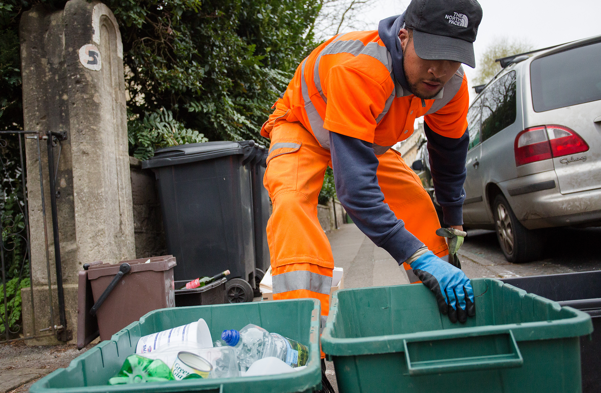A Bristol Waste recycling collector picking up green recycling boxes from the kerbside