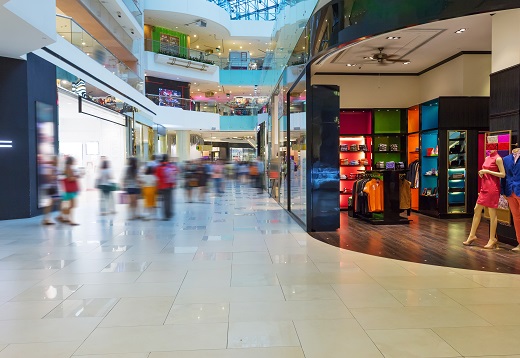 Image of a busy shopping centre with blurred images of people on the left and a open shop front with mannequins