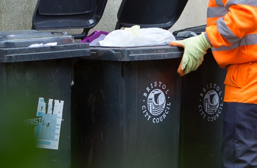 Bin with Bristol City Council logo on it and a figure in high vis opening it