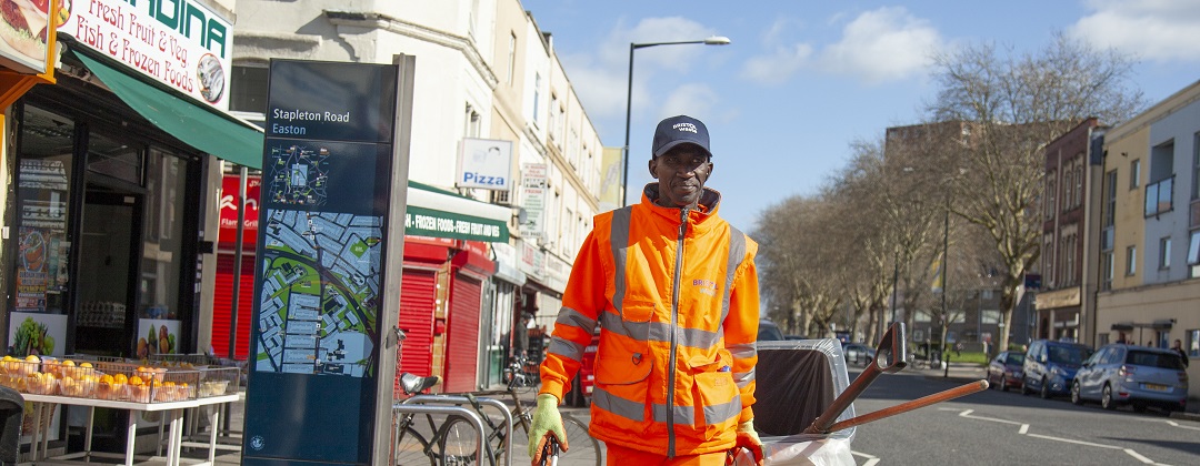 Street cleaning crew member walking along a Bristol road in high vis